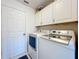 Clean laundry room with white washer and dryer, plus upper storage cabinets at 25110 Meriweather Rd, Leesburg, FL 34748