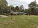 A traditional home featuring a lush green lawn, mature trees, and a well-maintained yard at 2930 Cr 416N, Lake Panasoffkee, FL 33538