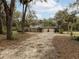 Two-story home with attached two-car garage surrounded by mature trees, and a sandy circular drive at 2930 Cr 416N, Lake Panasoffkee, FL 33538