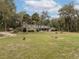 A traditional home featuring a lush green lawn, mature trees, and a well-maintained yard at 2930 Cr 416N, Lake Panasoffkee, FL 33538