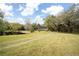 Scenic view of the property showcasing a tranquil pond surrounded by mature trees and a spacious lawn at 2930 Cr 416N, Lake Panasoffkee, FL 33538