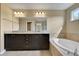 Well-lit bathroom features dual sinks, a large mirror, and a soaking tub, providing a luxurious experience at 30342 Gidran Ter, Mount Dora, FL 32757