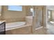 Well-lit bathroom features a soaking tub, glass-enclosed shower, and neutral tile flooring, providing a luxurious experience at 30342 Gidran Ter, Mount Dora, FL 32757