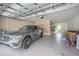 Attached garage with storage shelves, bright overhead lighting, and a gray luxury SUV parked inside at 30342 Gidran Ter, Mount Dora, FL 32757