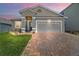Charming home featuring a two-car garage, brick driveway, neutral paint, and well-maintained landscaping at 3139 Hurston Watch Ln, Clermont, FL 34711