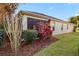 Exterior view of the back of the home featuring a screened lanai, lush landscaping, and a well-maintained lawn at 3144 Mayflower Loop, The Villages, FL 32163