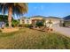 Beautiful single-story home with a well-manicured lawn and landscaping with various plants and a large palm tree at 3144 Mayflower Loop, The Villages, FL 32163