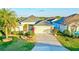 Charming single-story home featuring a well-manicured lawn, mature palm trees, and a two-car garage at 3144 Mayflower Loop, The Villages, FL 32163