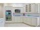 Well-lit kitchen with cream cabinets, granite countertops, stainless steel double ovens, cooktop and tile flooring at 3144 Mayflower Loop, The Villages, FL 32163