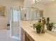 Bright bathroom featuring a glass-enclosed shower, soaking tub, and wooden vanity with large mirror at 3423 Capland Ave, Clermont, FL 34711