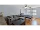 Bedroom with hardwood floors, a sofa, and a queen-sized bed near a window with sunlight at 3430 Turningwind Ln, Winter Garden, FL 34787