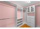 Large walk-in closet with custom shelving and drawers providing ample storage space in a pink-walled room at 3430 Turningwind Ln, Winter Garden, FL 34787