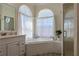 Bright bathroom featuring a soaking tub under two arched windows with sheer curtains at 39100 Tacoma Dr, Lady Lake, FL 32159