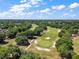 Expansive aerial view of a lush golf course surrounded by mature trees and a bright, sunny sky at 39100 Tacoma Dr, Lady Lake, FL 32159