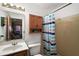 Functional bathroom with a single sink vanity, toilet, wooden medicine cabinet, and a shower with striped curtain at 40619 W 3Rd Ave, Umatilla, FL 32784