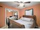 Bedroom featuring a wooden bed frame, ceiling fan, window with green curtains, and a mirrored sliding door closet at 40619 W 3Rd Ave, Umatilla, FL 32784