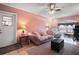 Cozy living room with pink walls, plush sofa, ceiling fan, and a large window, creating a comfortable space at 40619 W 3Rd Ave, Umatilla, FL 32784