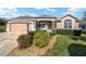 Charming home featuring a well-manicured lawn, beautiful landscaping, and a colorful front door at 447 Simpson St, The Villages, FL 32162