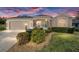 Charming home featuring a well-manicured lawn, beautiful landscaping, and a colorful front door at dusk at 447 Simpson St, The Villages, FL 32162