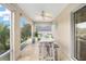 Bright enclosed lanai with a dining table, ceiling fan, and serene views of the surrounding greenery at 447 Simpson St, The Villages, FL 32162