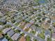Neighborhood aerial view with single-story home with well-manicured lawn with other homes, streets, and a pond nearby at 485 Pixie Ln, The Villages, FL 32162