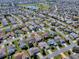 Neighborhood aerial view with single-story home with well-manicured lawn with other homes, streets, a golf course and pond nearby at 485 Pixie Ln, The Villages, FL 32162