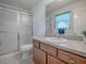 Bathroom with an enclosed shower and a vanity with wooden cabinets and a large mirror at 485 Pixie Ln, The Villages, FL 32162