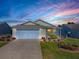 Charming single-story home with a well-manicured lawn and two-car garage with a lovely sunset in the background at 485 Pixie Ln, The Villages, FL 32162