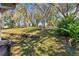 Backyard featuring a lush lawn, mature trees, and a retaining wall with garden bed at 519 Hearthglen Blvd, Winter Garden, FL 34787