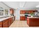 Well-lit kitchen with stainless steel appliances, cherry wood cabinets, tile floors and a view to the backyard at 519 Hearthglen Blvd, Winter Garden, FL 34787