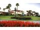 Elegant exterior view features a meticulously manicured lawn, blooming flowers, a clock tower, and statuesque palm trees at 54 Camino Real Blvd # 504, Howey In The Hills, FL 34737