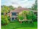Luxury villa exterior featuring a screened balcony overlooking a lush landscaped yard, complemented by tropical palm trees at 54 Camino Real Blvd # 504, Howey In The Hills, FL 34737