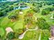 Scenic aerial view of lush golf course with mature trees, a serene pond, and meticulously manicured greens at 54 Camino Real Blvd # 504, Howey In The Hills, FL 34737