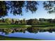 Golf course view of a sand trap and a serene lake mirroring trees, set against a building and a blue sky backdrop at 54 Camino Real Blvd # 504, Howey In The Hills, FL 34737