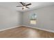 A bright bedroom with wood floors, neutral walls, and natural light from a large window at 565 Malauka Radl, Ocklawaha, FL 32179