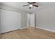 A bedroom with wood floors, neutral walls, a ceiling fan, and a sliding-door closet at 565 Malauka Radl, Ocklawaha, FL 32179