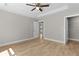 A bedroom with wood-look flooring, neutral walls, a ceiling fan, and an attached closet at 565 Malauka Radl, Ocklawaha, FL 32179