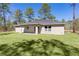Home's rear exterior view, complete with covered patio, and verdant lawn at 565 Malauka Radl, Ocklawaha, FL 32179