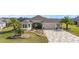 Well-manicured home exterior featuring a two-car garage, lush landscaping, and a paver driveway at 712 Krietemeyer Path, The Villages, FL 32163