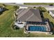 Aerial view of home featuring a screened-in pool, patio, and well-manicured landscaping at 712 Krietemeyer Path, The Villages, FL 32163