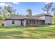 A spacious backyard features a large lawn and comfortable, screened in patio at 73 Bay Dr, Ocklawaha, FL 32179