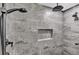 Modern shower featuring multiple shower heads, grey marble-style tile, and a recessed shelf for storage at 73 Bay Dr, Ocklawaha, FL 32179