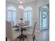 This dining area features a glass table, beige chairs, and abundant natural light from large, shuttered windows at 7812 Se 167Th Mistwood Ln, The Villages, FL 32162