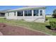 Rear exterior view featuring a sunroom addition and well-maintained landscaping at 7812 Se 167Th Mistwood Ln, The Villages, FL 32162