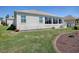 Rear exterior of home, with a sunroom addition, showcasing the landscaped backyard at 7812 Se 167Th Mistwood Ln, The Villages, FL 32162