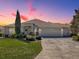A well-manicured lawn and mature trees frame this home with a triple-car garage and elegant entrance at 7812 Se 167Th Mistwood Ln, The Villages, FL 32162