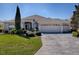 Charming front exterior with a well-manicured lawn, mature trees, and a three-car garage at 7812 Se 167Th Mistwood Ln, The Villages, FL 32162