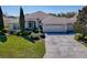 Inviting front exterior view with a large driveway, manicured landscaping, and a three-car garage at 7812 Se 167Th Mistwood Ln, The Villages, FL 32162