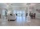 This living room features an open floor plan, white furniture, wood-look floors, and sliding glass doors to the lanai at 7812 Se 167Th Mistwood Ln, The Villages, FL 32162