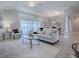 This spacious living room features an open floor plan, white furniture, wood-look floors, and view to the lanai at 7812 Se 167Th Mistwood Ln, The Villages, FL 32162